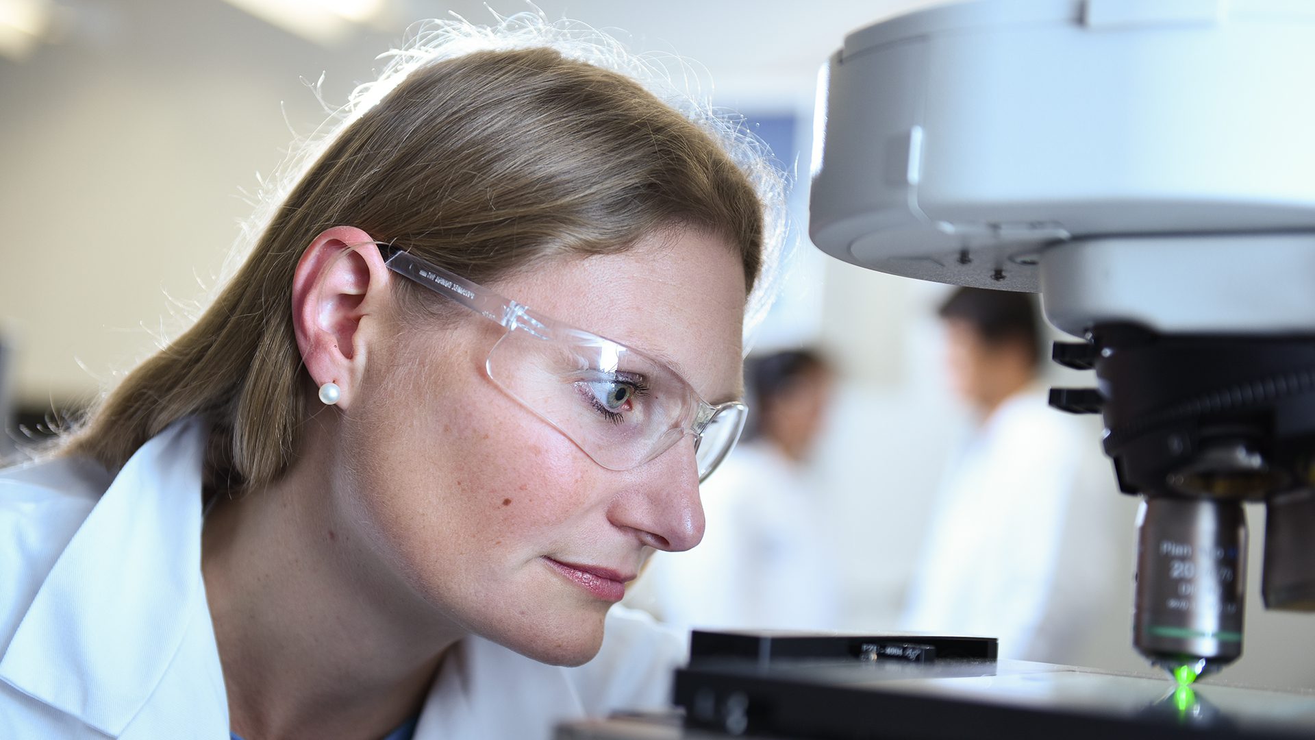 Scientist with safety glasses near microscope
