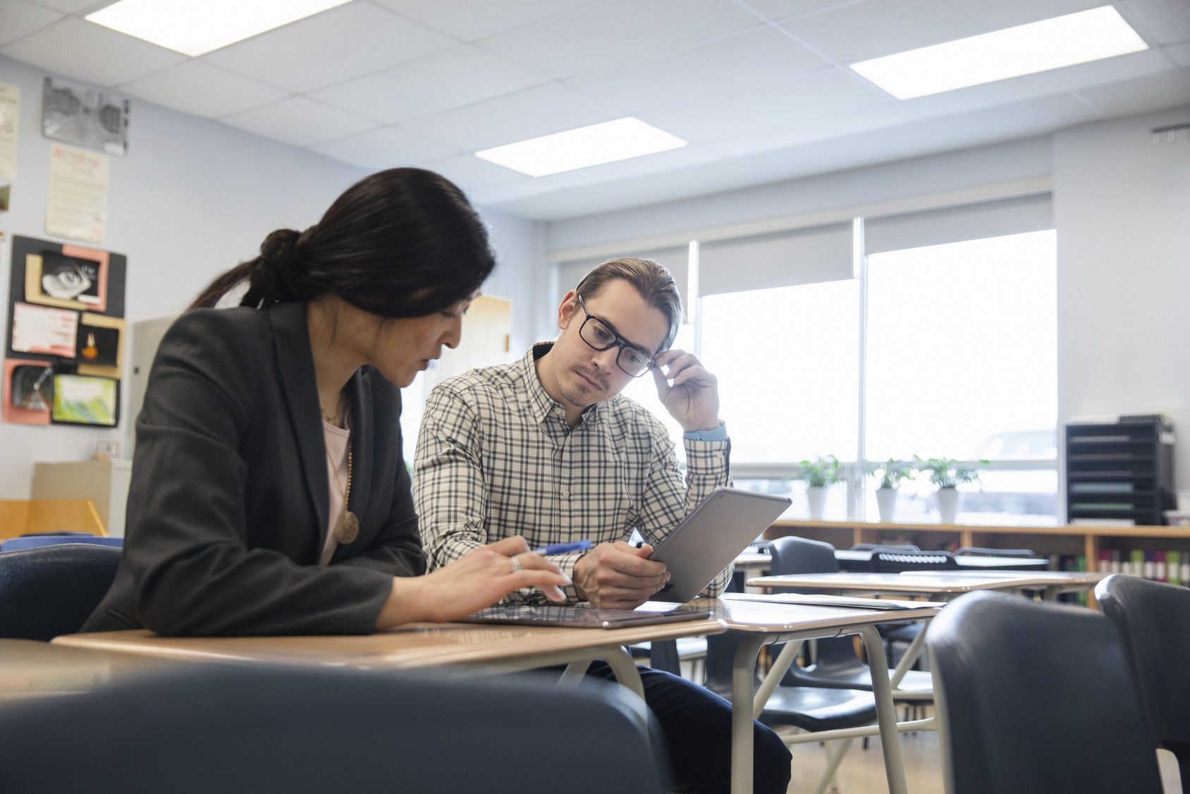 High school teachers with digital tablets talking in classroom
