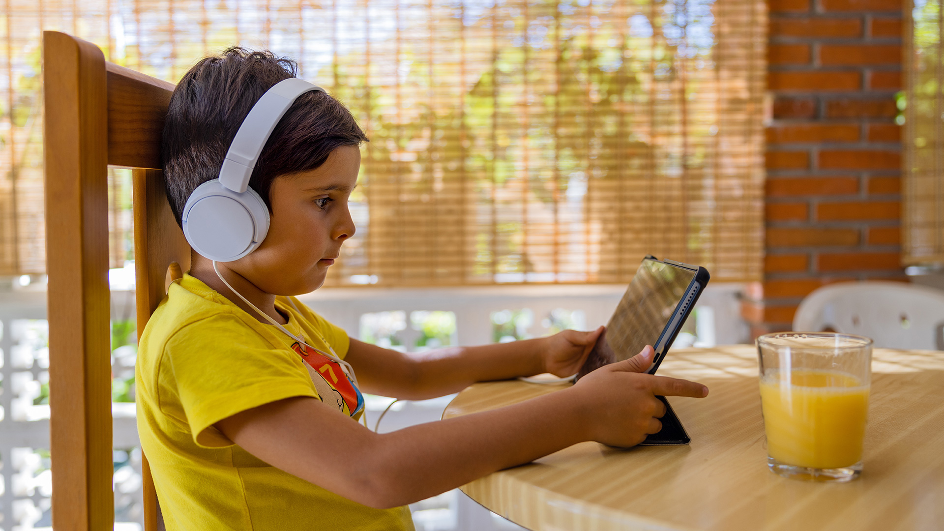 Young boy watching a tablet at breakfast